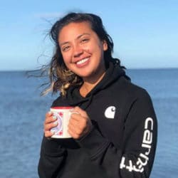 Denali by the ocean holding a coffee mug